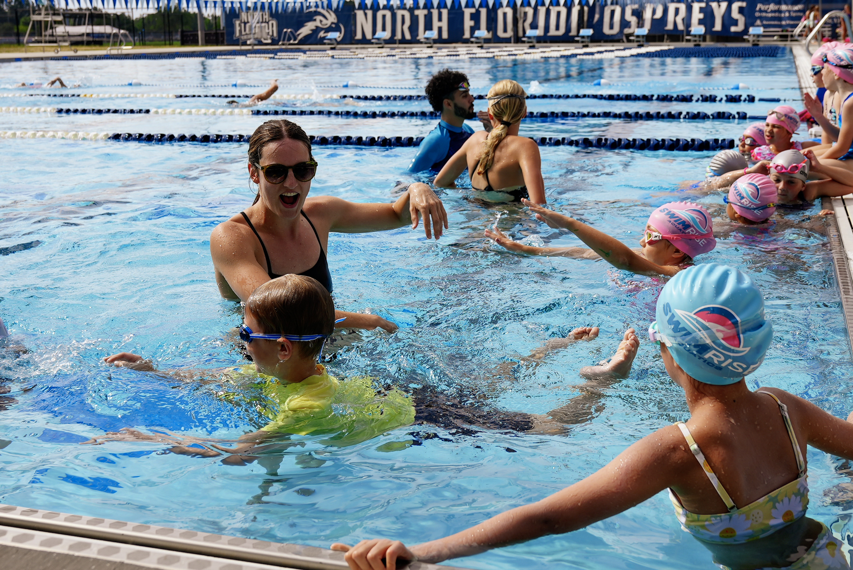 Professional swim instructor teaching in a clear blue swimming pool